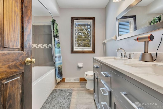 bathroom with toilet, baseboards, wood finished floors, and plenty of natural light