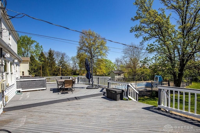 wooden deck featuring outdoor dining space, a storage unit, and an outdoor structure