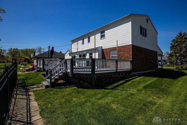 back of property with a deck, fence, a yard, and brick siding