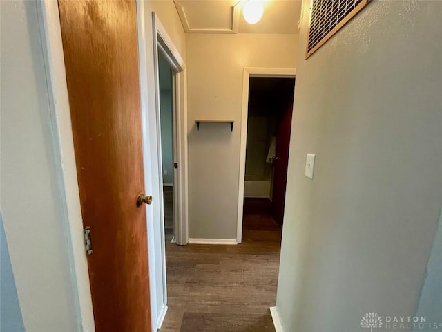 hall featuring visible vents, wood finished floors, and baseboards