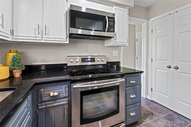 kitchen featuring appliances with stainless steel finishes, white cabinetry, and dark stone countertops