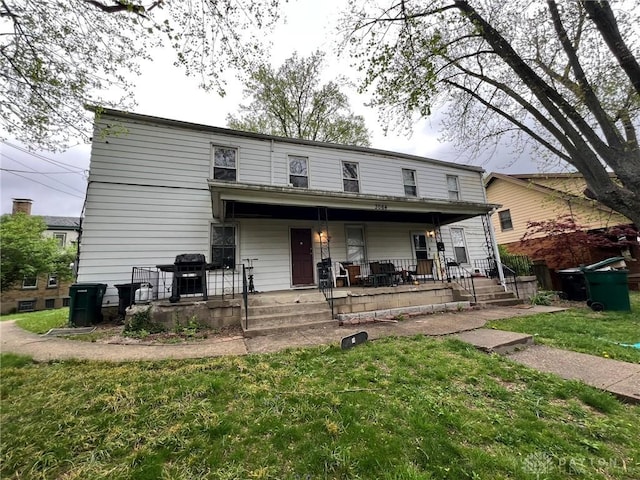 back of house featuring covered porch and a lawn
