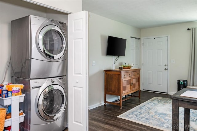 laundry room with dark wood finished floors, baseboards, stacked washer and dryer, and laundry area