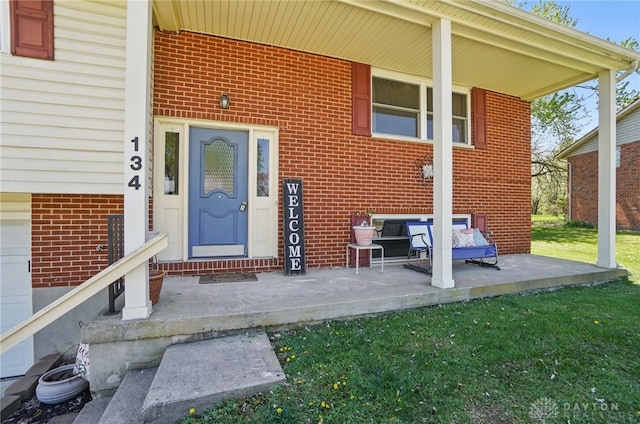 entrance to property with a yard and brick siding