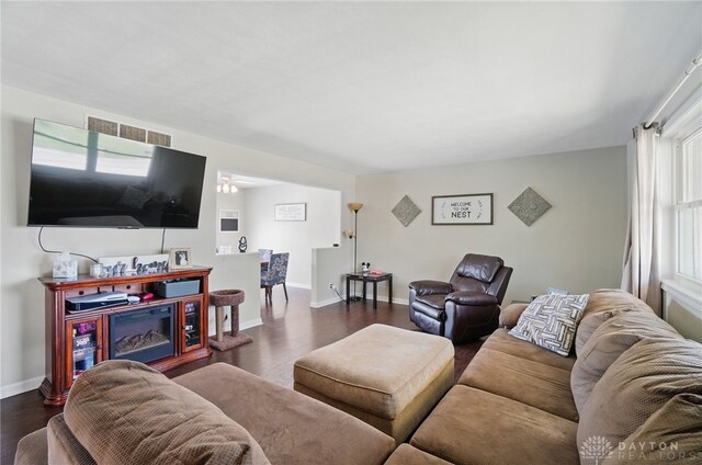 living room with dark wood-style floors, visible vents, and baseboards