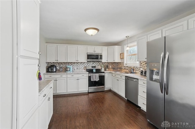 kitchen featuring white cabinetry, appliances with stainless steel finishes, decorative backsplash, and a sink