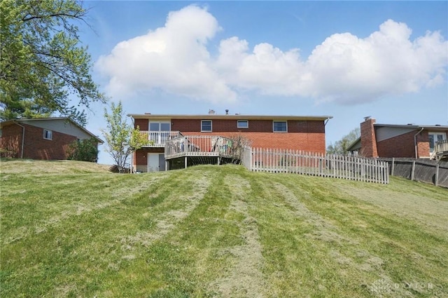 rear view of property with fence, a yard, and brick siding