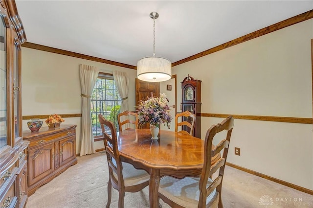 dining room with crown molding, baseboards, and light carpet