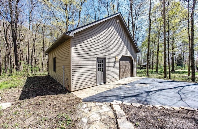 view of outbuilding with a wooded view and aphalt driveway