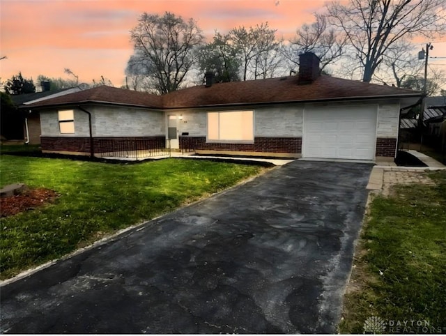view of front facade featuring driveway, a yard, brick siding, and a garage