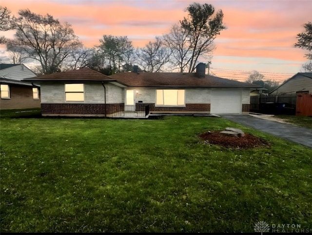 view of front of home with a garage, brick siding, aphalt driveway, and a lawn