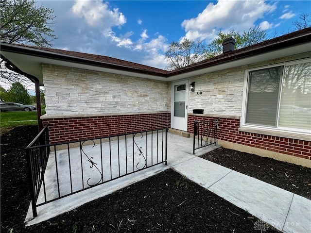 property entrance with a chimney and stone siding