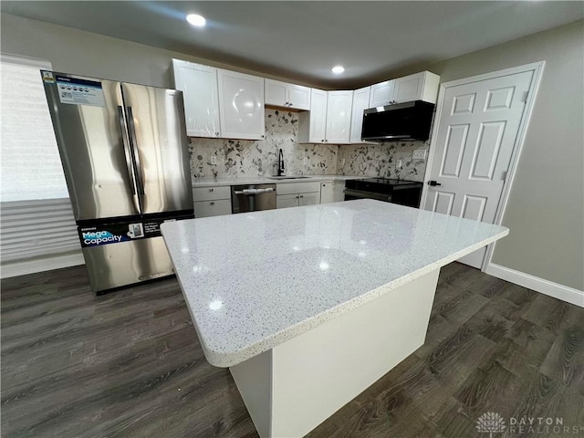 kitchen with white cabinetry, stainless steel appliances, light stone countertops, and a sink