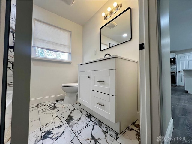bathroom featuring vanity, toilet, marble finish floor, and baseboards