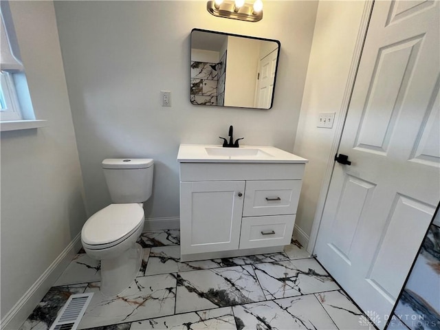 bathroom featuring toilet, marble finish floor, and baseboards