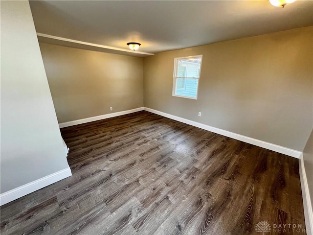 empty room featuring dark wood finished floors and baseboards