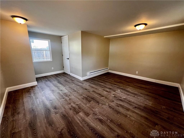 empty room featuring baseboards, a baseboard heating unit, and dark wood-style flooring