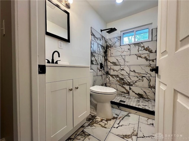 bathroom featuring vanity, a tile shower, toilet, and marble finish floor