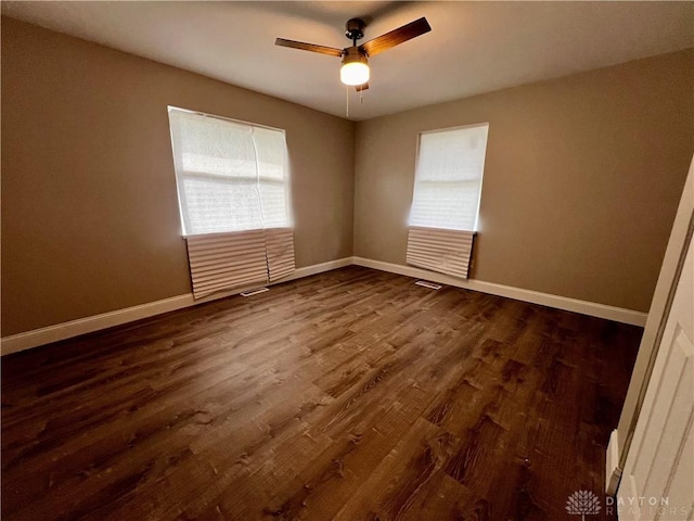 spare room with dark wood-type flooring, baseboards, a healthy amount of sunlight, and ceiling fan