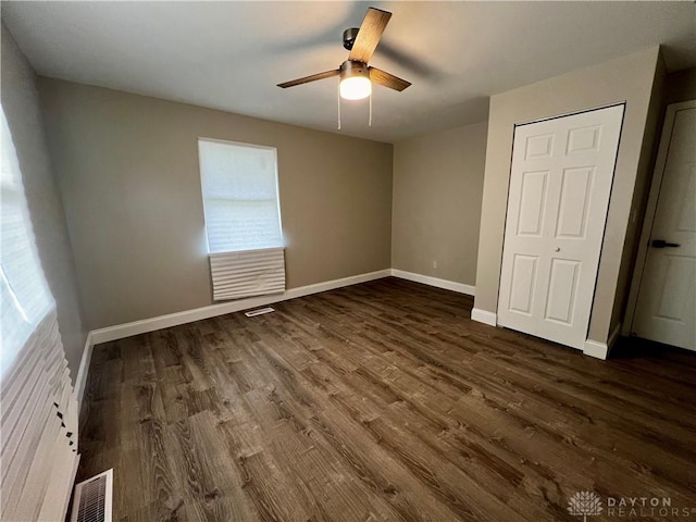 unfurnished bedroom with dark wood finished floors, visible vents, ceiling fan, and baseboards