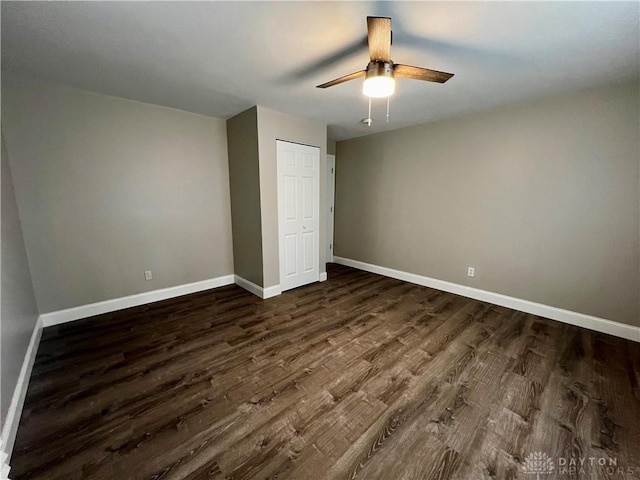 unfurnished bedroom with a ceiling fan, dark wood-style floors, and baseboards
