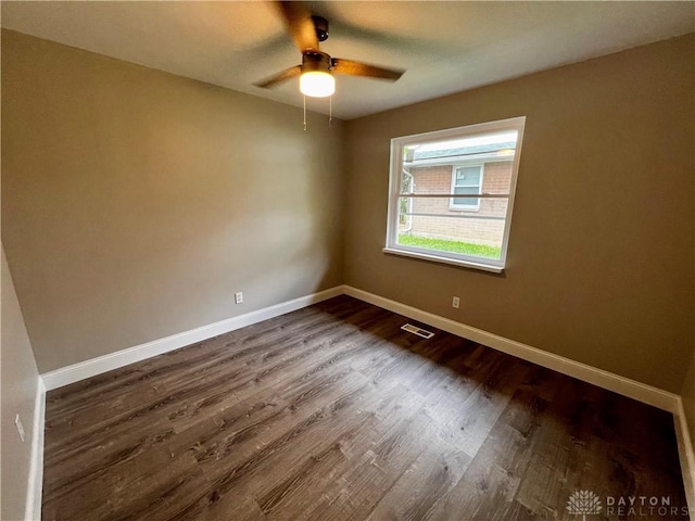 spare room featuring dark wood-style floors, visible vents, ceiling fan, and baseboards