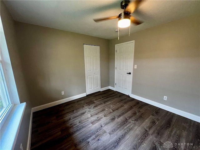 spare room with baseboards, a ceiling fan, and dark wood-style flooring