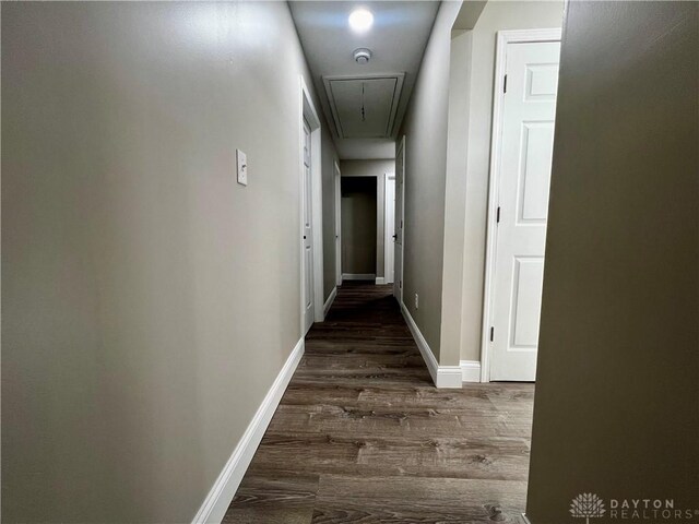 corridor with dark wood-style floors, baseboards, and attic access