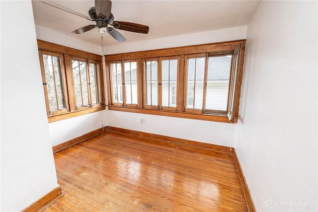 spare room with a ceiling fan, light wood-style flooring, and baseboards