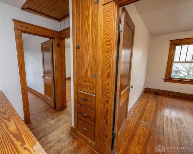 hall with baseboards and wood-type flooring