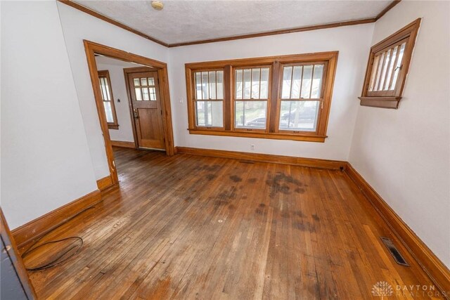 interior space with visible vents, baseboards, crown molding, and wood-type flooring