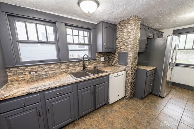 kitchen featuring a textured ceiling, decorative backsplash, dishwasher, and a sink
