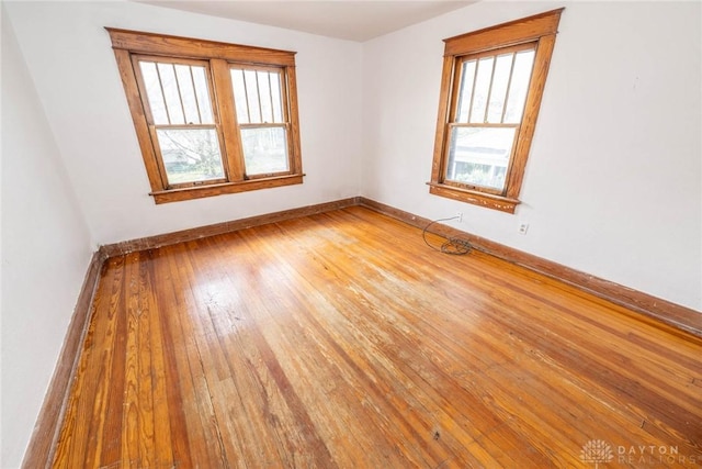 unfurnished room with wood-type flooring and baseboards