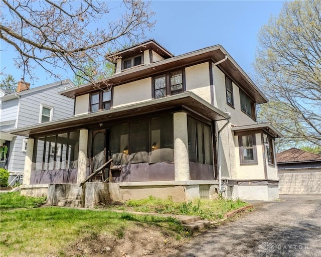 rear view of house with stucco siding and a sunroom