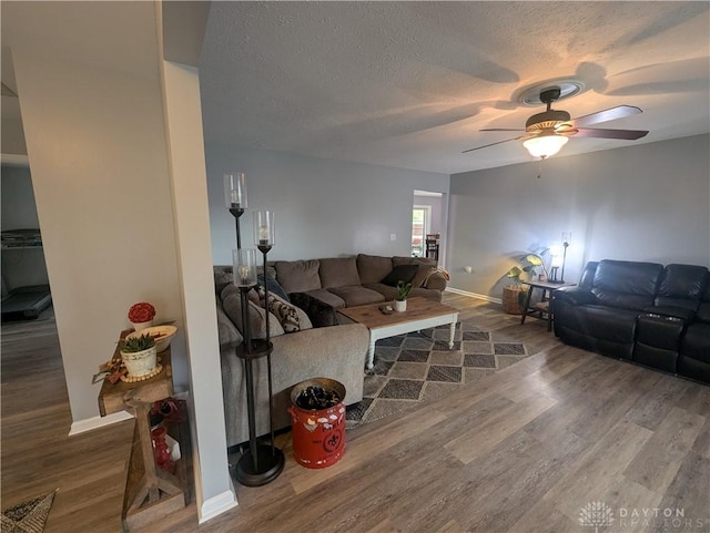 living area with a ceiling fan, baseboards, wood finished floors, and a textured ceiling