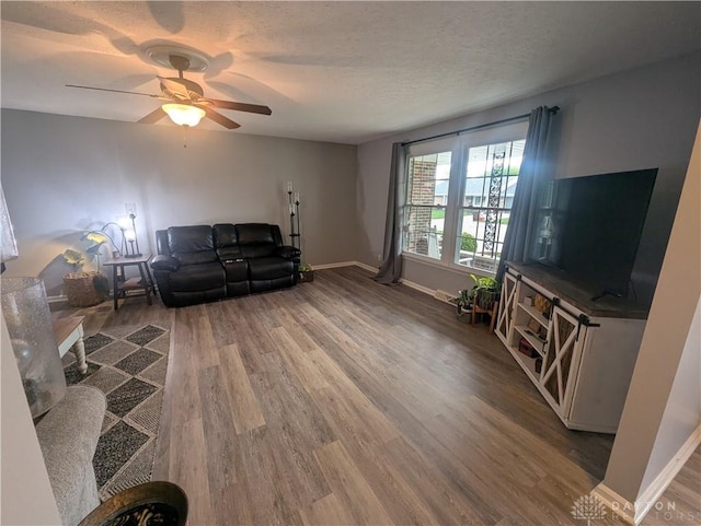 living room featuring wood finished floors, a ceiling fan, and baseboards