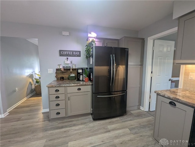 kitchen with light wood-style flooring, gray cabinetry, freestanding refrigerator, and baseboards