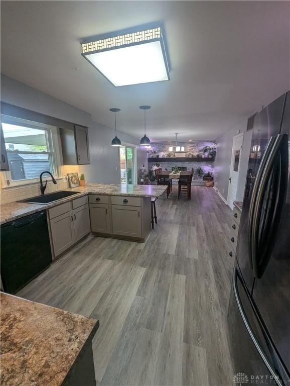 kitchen featuring black appliances, a healthy amount of sunlight, a peninsula, and a sink