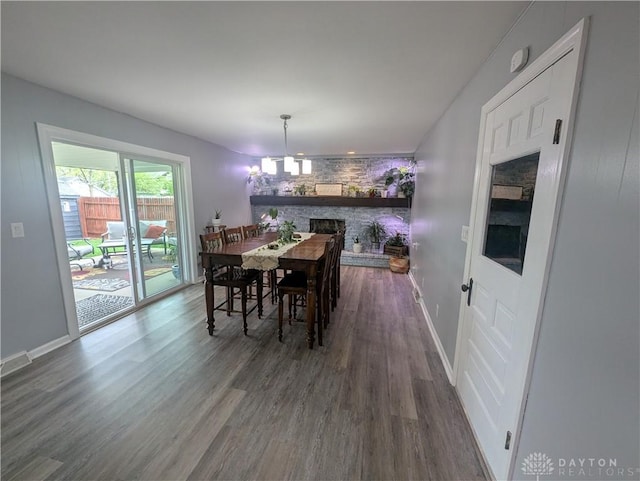 dining space with a fireplace, dark wood finished floors, and baseboards