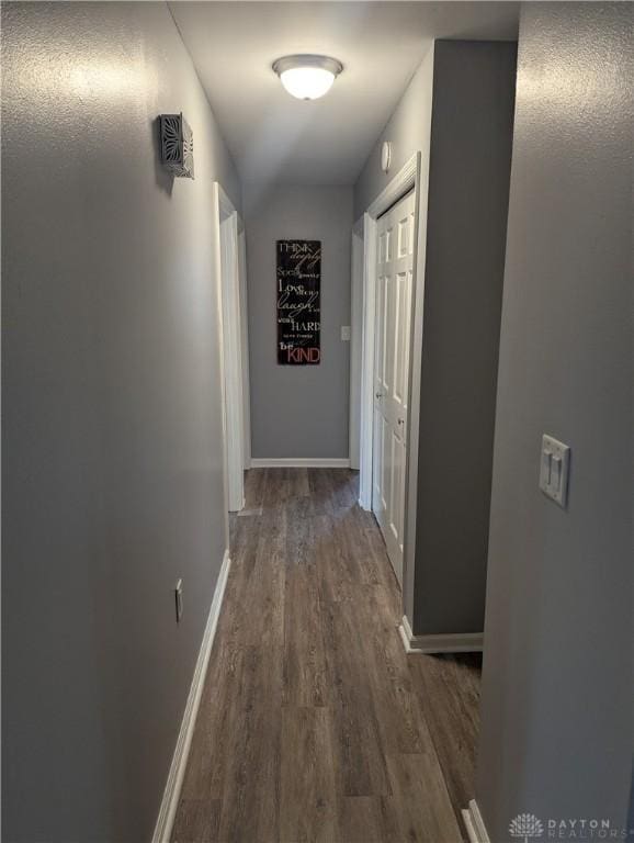 hall with baseboards and wood finished floors