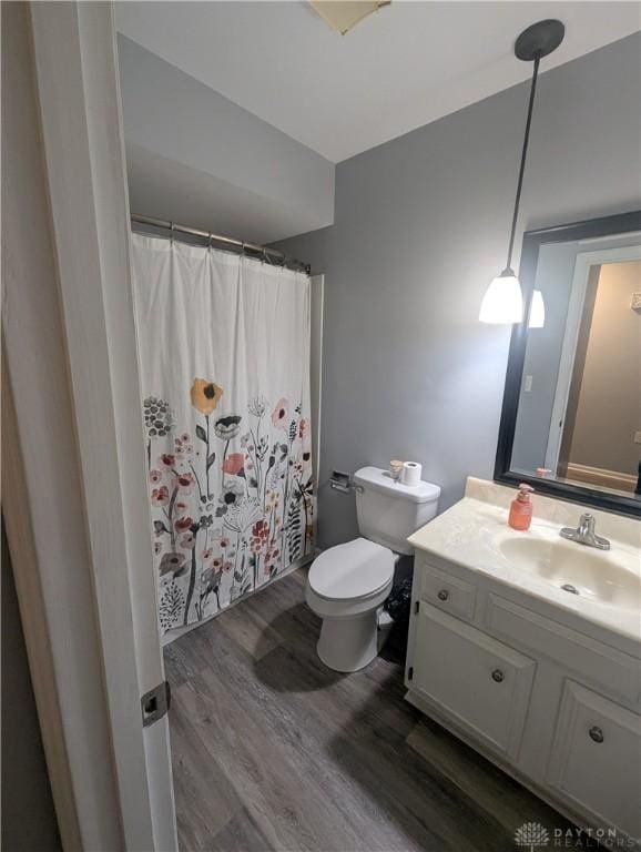 bathroom with toilet, vanity, a shower with curtain, and wood finished floors