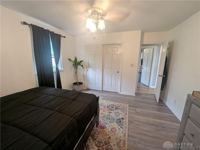 bedroom featuring wood finished floors, baseboards, a ceiling fan, and a closet