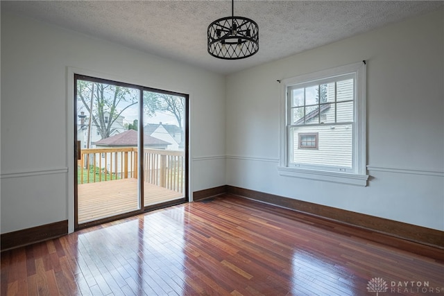 9 Wiltshire Blvd, Oakwood, OH 45419 - empty room with dark wood-type flooring, a textured ceiling, a notable chandelier, and baseboards