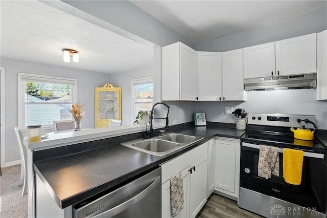 1708 Patterson Rd, Dayton, OH 45420 - kitchen with under cabinet range hood, stainless steel appliances, a sink, dark countertops, and a peninsula