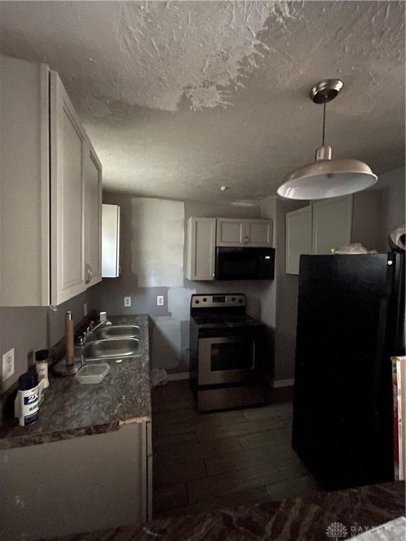kitchen featuring black appliances, baseboards, white cabinets, and a sink
