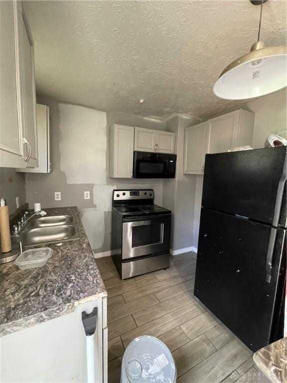 kitchen with black appliances, a sink, wood tiled floor, and baseboards