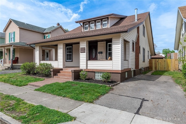 bungalow-style house featuring covered porch, fence, a gate, and a shingled roof