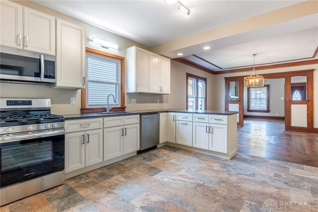kitchen featuring a peninsula, a sink, appliances with stainless steel finishes, and stone finish flooring