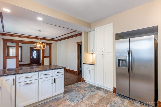 kitchen with baseboards, stone tile flooring, white cabinetry, stainless steel refrigerator with ice dispenser, and a notable chandelier