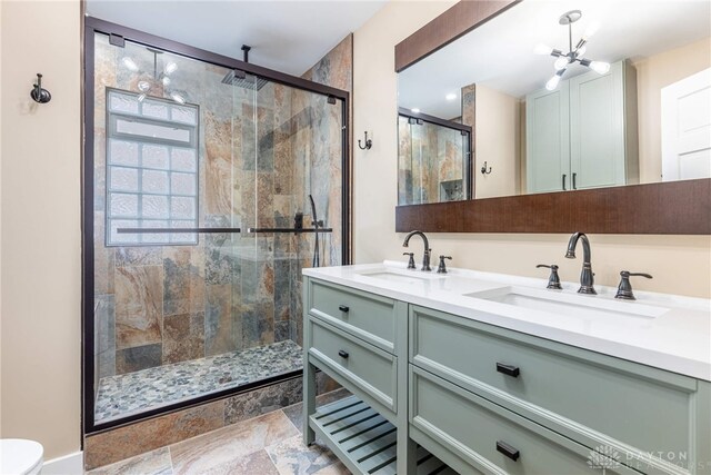 full bath featuring a stall shower, double vanity, a sink, and a chandelier